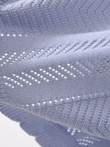 Close-up of light blue knit fabric with geometric hollow patterns and soft texture