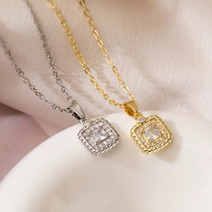 Elegant gold and silver square zircon pendant necklaces displayed on a ceramic tray
