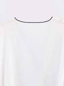 Detail einer weißen Baumwoll-Leinen-Bluse mit Rundhals und schwarzer Paspel am Rücken