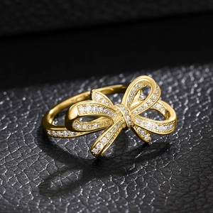 Vue détaillée d'une bague nœud dorée avec zircons brillants sur fond de cuir noir