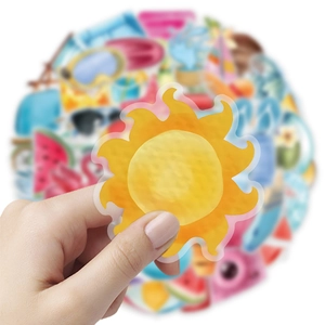 Close-up of hand holding a waterproof yellow sun sticker from a summer beach set