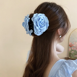 Detail einer großen blauen Organza-Rose Haarklammer, am Haar einer Frau gestylt