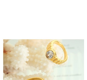 Detail view of a gold-plated textured ring featuring a round clear cubic zirconia stone