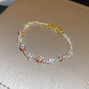 Detailed macro shot of elegant gold flower bracelet with pink and white cubic zirconia