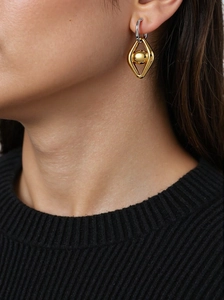 Détail d'une boucle d'oreille géométrique dorée avec touches d'argent sur un modèle