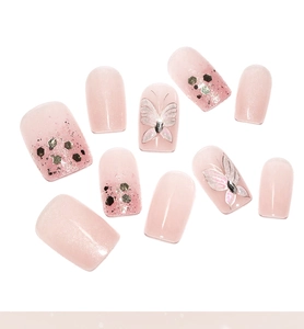 Detail of pink press-on nails featuring glitter gradient and silver butterfly with rhinestones