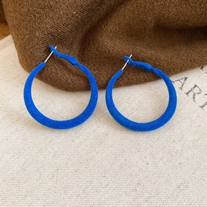 Vue détaillée des boucles d'oreilles créoles bleu roi avec une texture floquée mate