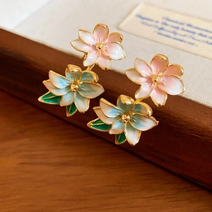 Detail of elegant enamel flower earrings with delicate pink petals and green leaf accents