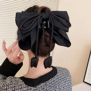 Détail d'une grande pince à cheveux avec nœud noir et de longs pompons élégants