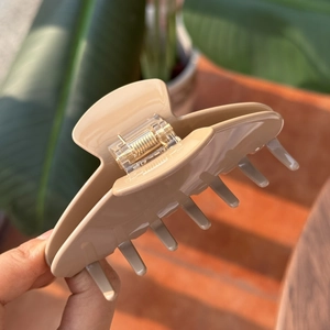 Close-up of elegant apricot acetate hair claw clip held by hand in soft sunlight