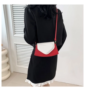Détail d'un sac bandoulière rouge et blanc avec relief cœur porté à l'épaule