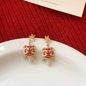 Macro detail of Chinese lion dance earrings with red enamel and white pearl drops