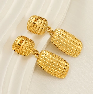 Close-up of gold-plated square checkered earrings with textured geometric patterns