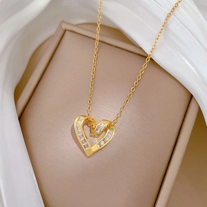 Detail of a gold heart pendant with zircon crystal on white silk and brown box