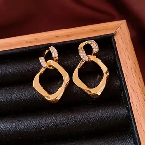Goldene geometrische Ohrringe mit Zirkonia-Inlay in einer schwarzen Schmuckschachtel