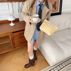Model holding a large yellow and white striped toiletry bag in a stylish living room
