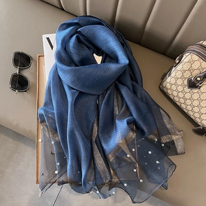 Detail of dark blue silk scarf with delicate gold trim and sewn pearl embellishments