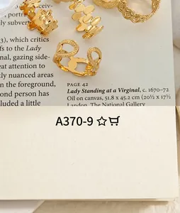 Detail of 18K gold-plated C-shaped earrings with zircon inlay on art magazine background