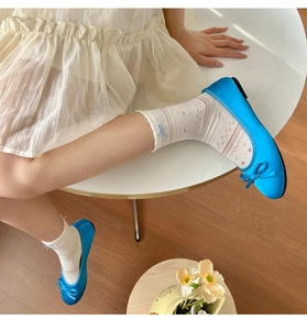Detail of bright blue satin ballet flats with bow ornament and white lace socks