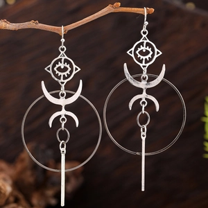 Silver bohemian long earrings with moon and eye symbols hanging on a branch