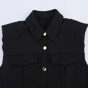 Detail of black sleeveless dress with lapel collar, gold metal buttons and front pockets