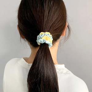 Detail of two-tone light blue and yellow satin scrunchie on a ponytail hairstyle
