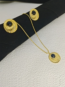 Detail of gold shell textured necklace and earrings with round black gemstones