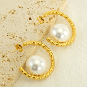 Detailed shot of gold C-shaped twisted earrings featuring large high-luster white pearls