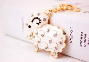 Sparkling rhinestone sheep keychain in white enamel with gold metal and iridescent bead