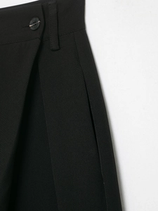 Detailed view of women's black trousers featuring an asymmetrical waist and button closure