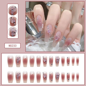 Detail of pink gradient press-on nails with 3D butterflies, roses, and pearls