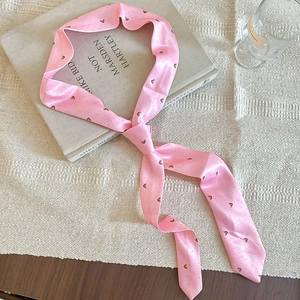 Silk-textured pink ribbon scarf with black butterfly print tied on an art book