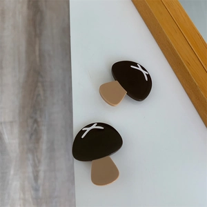 Detail view of cute mushroom shaped brown acetate hair clips on a wooden background