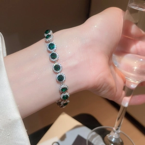 Bracelet élégant en zircon vert avec monture argentée porté au poignet pour soirée