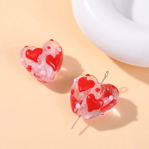 Macro shot of a pink heart-shaped glass bead with red dots for DIY jewelry making