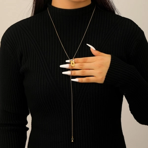 Detail of a golden Y-shaped long necklace with red gemstone and adjustable slider