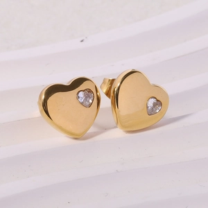 Detail of 18K gold heart stud earrings with inlaid cubic zirconia on textured surface