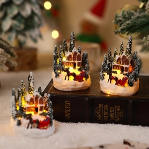 Detail of glowing resin Christmas village house with warm LED lights and red sleigh