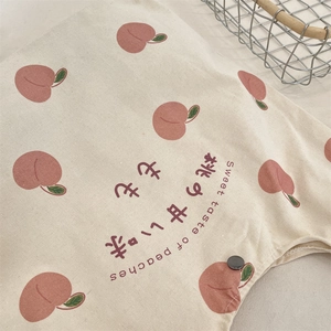 Close-up of fresh peach print on beige canvas tote with metal snap button closure