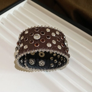 Gros plan sur un bracelet large en cuir embossé avec cristaux blancs et ambrés