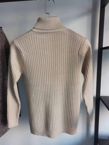 Dettaglio di un maglione beige a collo alto con trama in maglia a righe verticali