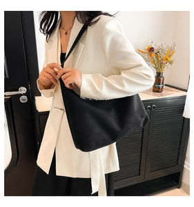 Detail of a large black tote bag held by a model in a professional indoor lifestyle setting