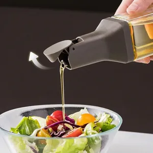 Glass oil dispenser bottle with automatic gravity lid pouring oil onto a fresh salad