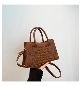 Close-up of brown crocodile texture material and handle on a stylish tote bag