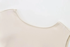Detailed macro view of the sleek beige neckline with fine stitching on a woven dress
