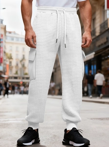 Detailed close-up of men's white waffle texture cargo joggers with large utility side pockets