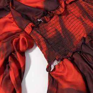 Detailed close-up of smocked waist with red black gradient print and ruffle trim