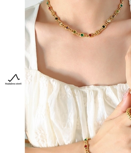 Model wearing stainless steel jewelry set with colorful round gemstones and gold finish
