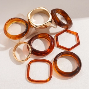 Set aus bernsteinfarbenem Acryl und goldfarbenem Metall Armreifen in geometrischen Formen