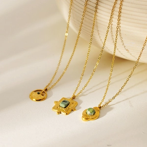 Vintage gold-plated stainless steel necklaces with natural turquoise pendants on pottery